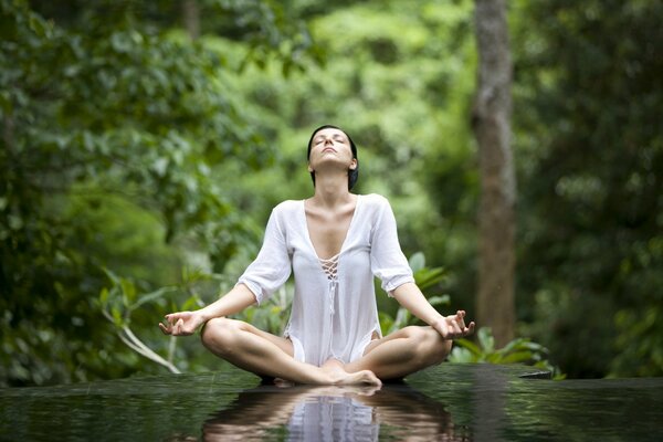 Donna che medita sulla natura nella posizione del loto