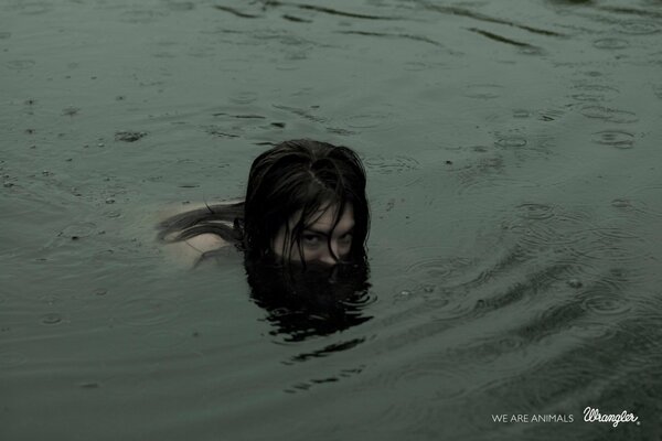 Ragazza che nuota in un lago notturno. Solo la testa sporge sopra l acqua