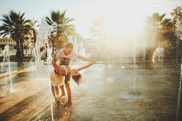 Los amantes bailan en una fuente con un telón de fondo de palmeras