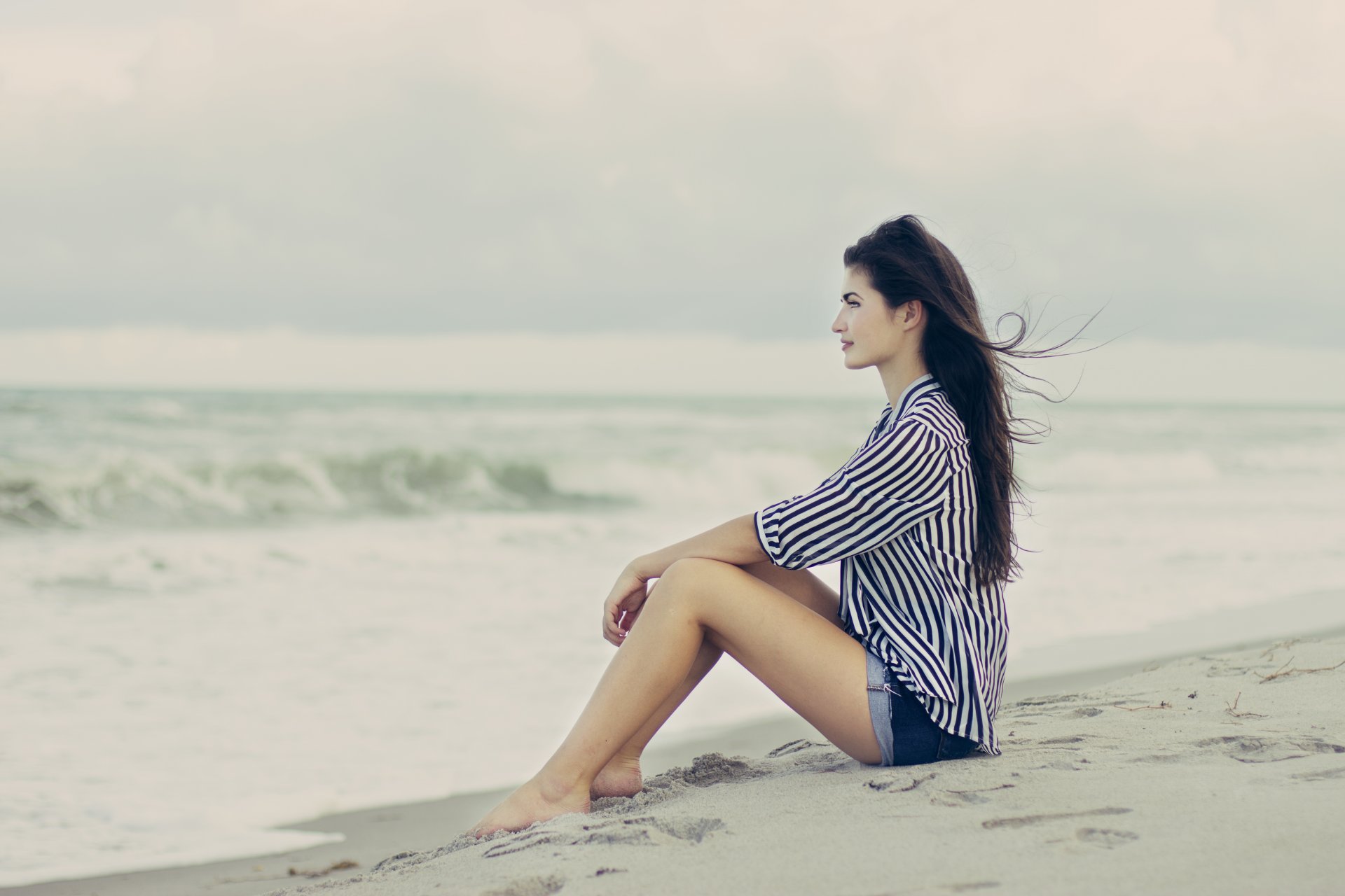 la jeune fille la brune la plage le sable le vent le profil la posture assis