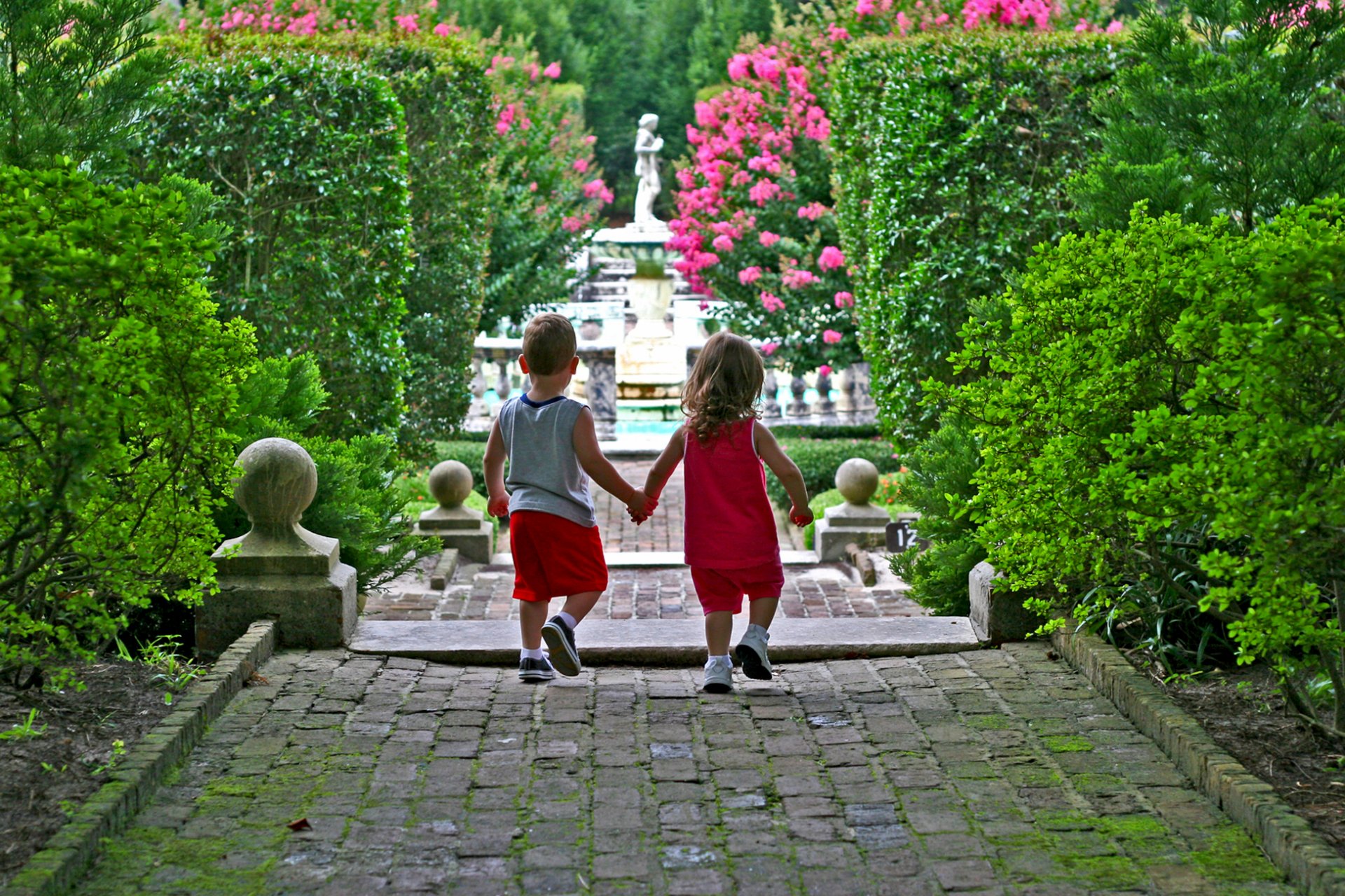 le parc les enfants le garçon la fille la statue de la piste de roses de fleurs d arbustes haie