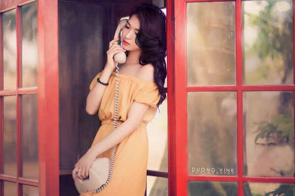 Ragazza asiatica in cabina telefonica