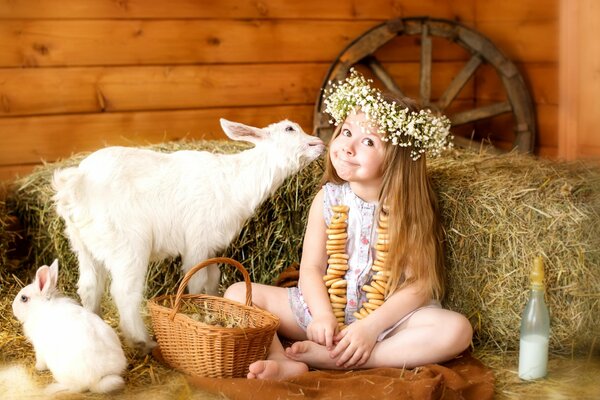 Ein Mädchen im Kranz, das eine Ziege und ein Kaninchen füttert