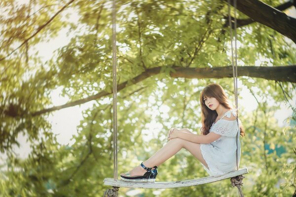 Chica en un columpio de cuerda en un árbol