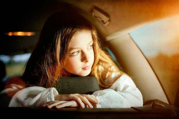 Una niña Mira por la ventana de un coche