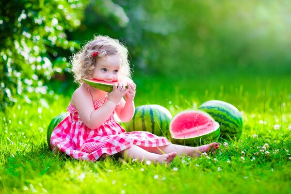 Ragazza in abito che mangia anguria sul prato