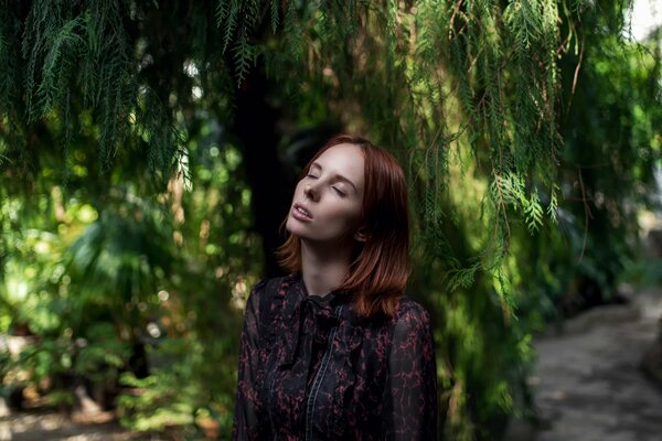 Una chica con los ojos cerrados se encuentra debajo de un árbol