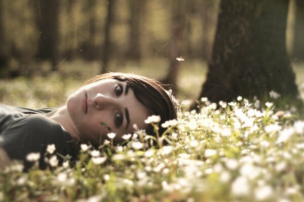 Mädchen im Wald liegt auf Blumen