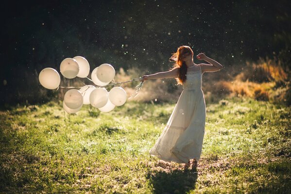 La jeune fille au milieu des champs avec des boules dans les mains