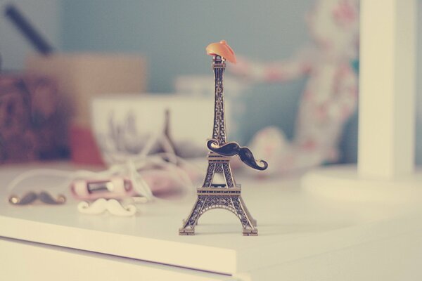 Piccola Torre Eiffel sul tavolo con cappello e baffi