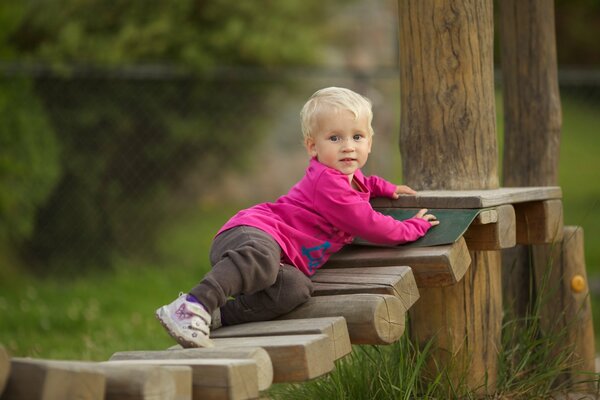 A little boy is playing on a wooden ladder