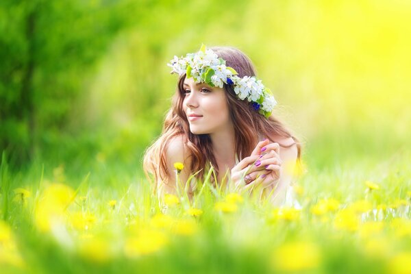Una ragazza dai capelli scuri meditabonda in una corona di fiori nell erba