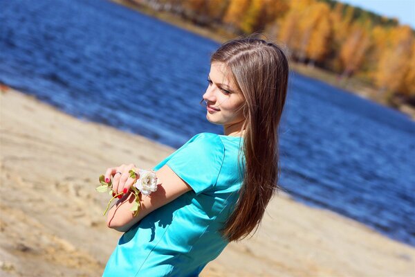 Dark-haired girl with a white rose by the sea