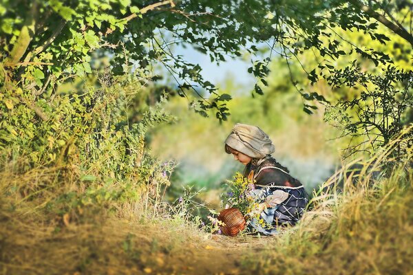 Niña en verano en la naturaleza con una cesta de flores