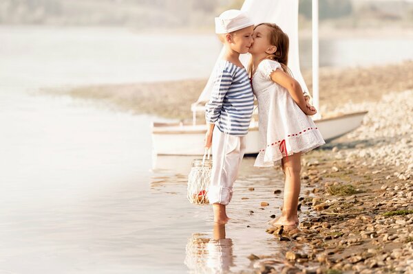 Fille baiser garçon en marin sur la plage
