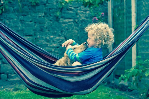 Happy child with a dog in a hammock