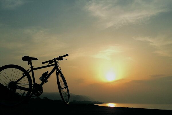 Fahrrad steht bei Sonnenuntergang am Seeufer