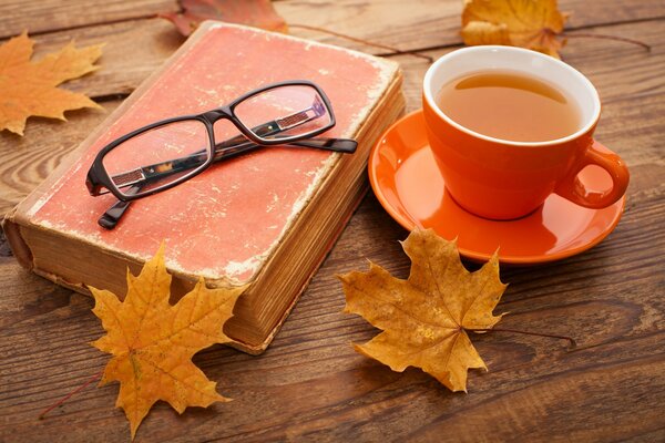 Jesień, opadanie liści, filiżanka herbaty na stole