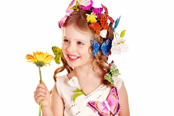 La ragazza adorabile con le farfalle nei capelli tiene il fiore
