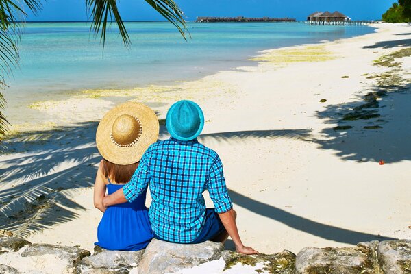 Pareja enamorada con sombreros en la playa