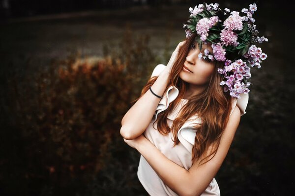 A girl with a wreath on a dark background of nature