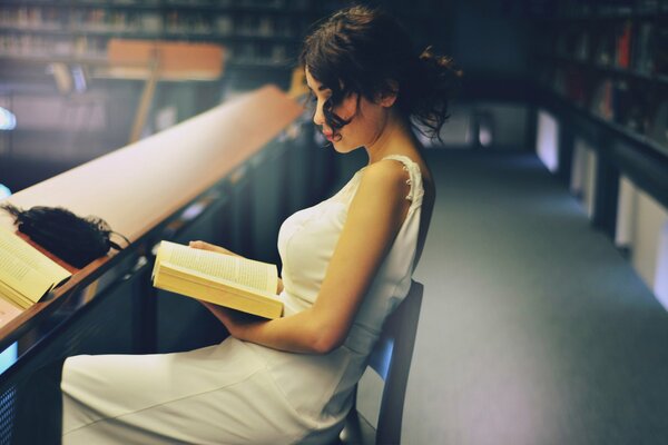 Beautiful girl reading a book in the library