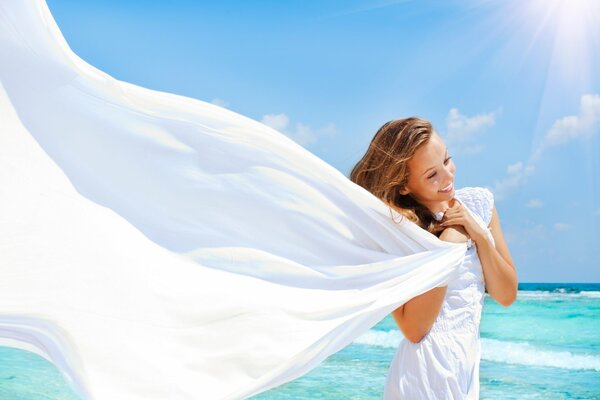 Ragazza in abito bianco con sorriso sullo sfondo del mare