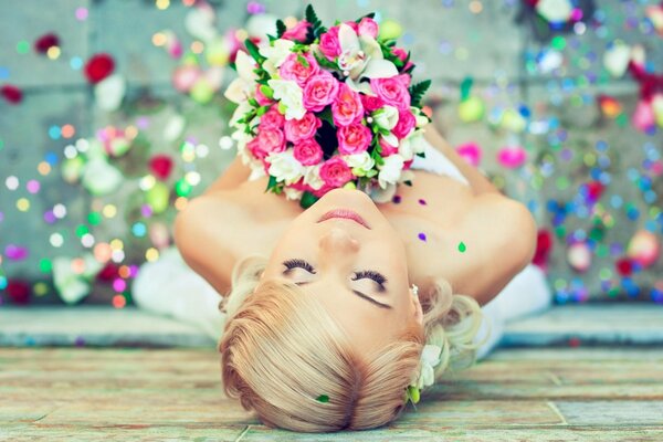 Die Braut mit einem Blumenstrauß liegt auf dem Boden