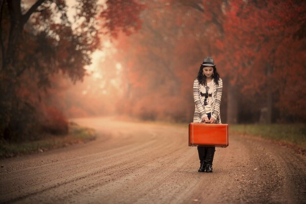 Chica con una maleta esperando el otoño dorado