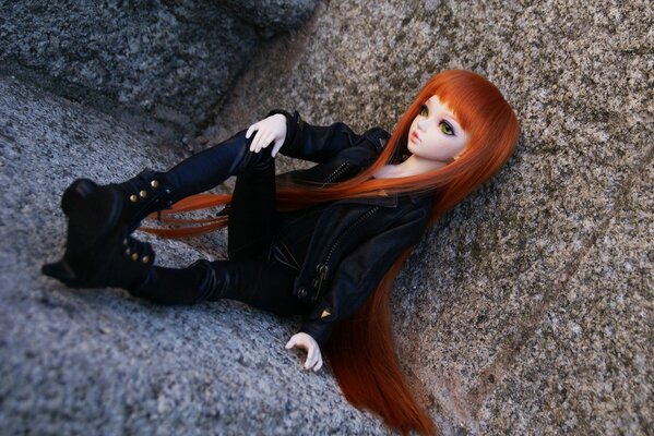 Poupée avec de longs cheveux roux assis sur un rocher