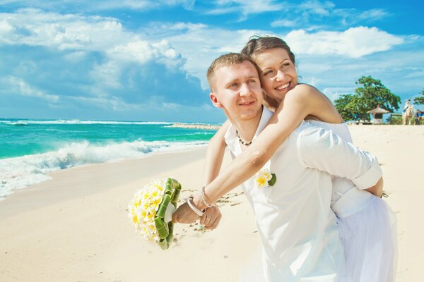 Pareja enamorada en la arena blanca del océano con un ramo de margaritas