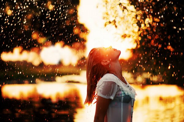 A girl enjoys the rain at sunset