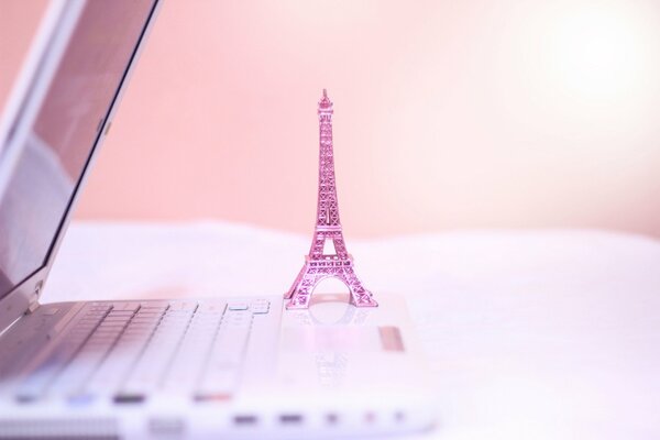 Розовая статуэтка эйфелевой башни на ноутбуке