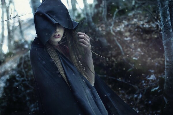 Ragazza con cappuccio nero in mezzo alla foresta