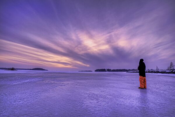 A guy on ice admires the lilac sky in Sweden