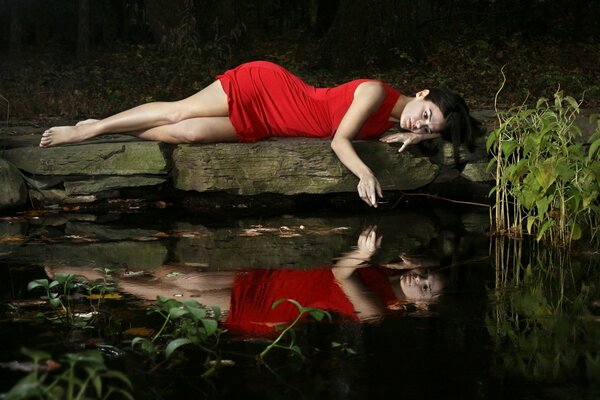 La fille en rouge sur un rocher au bord d un lac est triste