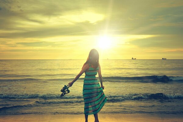 Mädchen im Kleid am Strand auf Sonnenuntergang Hintergrund