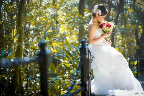 Mujer asiática en vestido de novia sostiene un ramo de flores