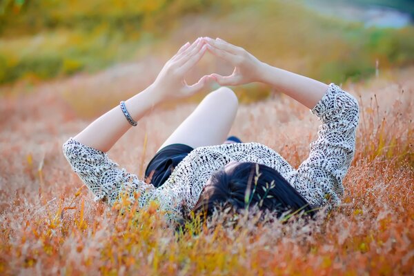 Chica en el campo y el gesto del corazón