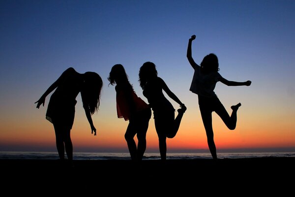 Sagome di ragazze in riva al mare sullo sfondo del tramonto