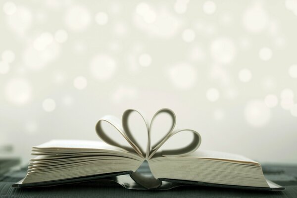 There is an open book with the pages folded in the form of a heart