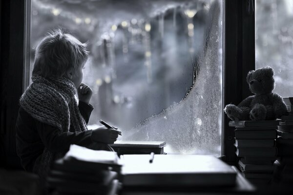 Le garçon regarde par la fenêtre l hiver