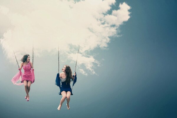 Girls in beautiful dresses swing on a heavenly swing