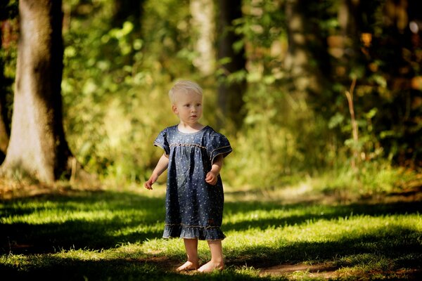 A baby in a dress in a forest clearing