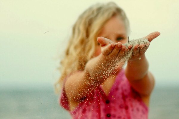 The girl and the sand flowing through her fingers