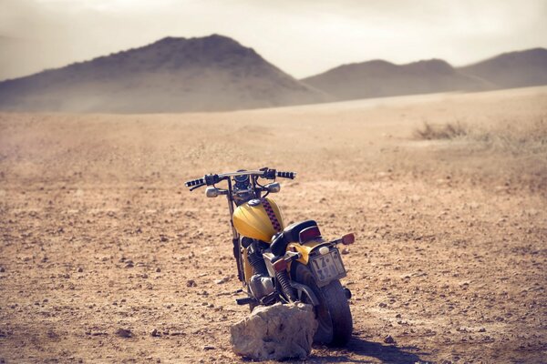 An old motorcycle in a field against the background of hills