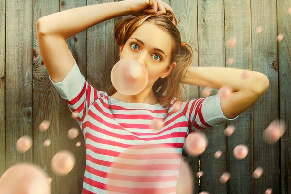 A girl inflates a bubble from a yawning gum