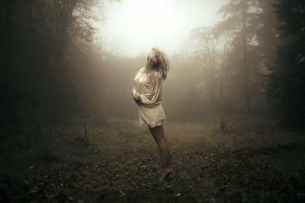 Chica de pie en el bosque de niebla