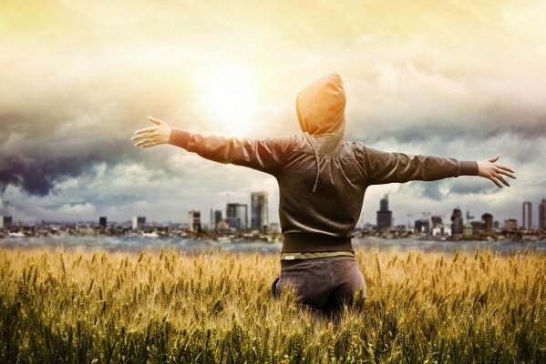 A girl dressed in a hooded sweatshirt in a wheat field