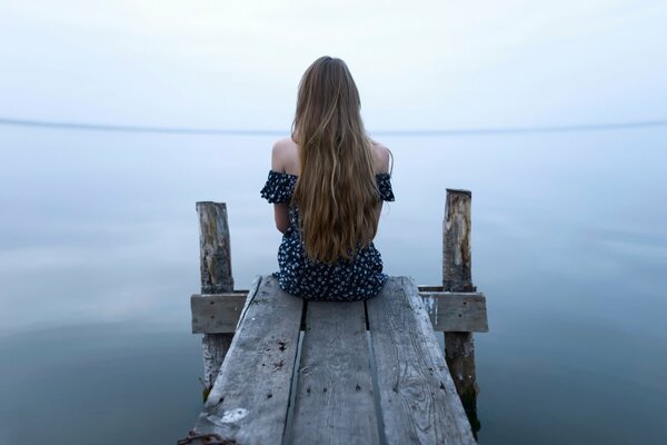 Long-haired girl sitting by the water